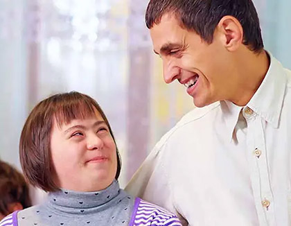 A young woman smiles as she looks up into the face of her carer.