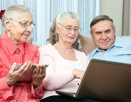 Three elderly people are reading the policy and procedures on a laptop.