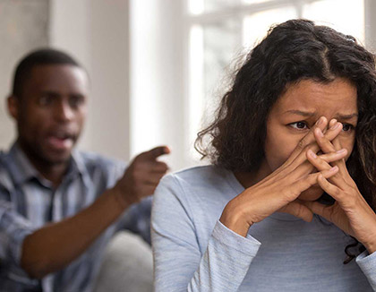 An woman shields herself whilst a man grabs her by the wrist.