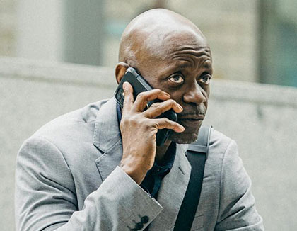 A concerned man in a suit is using his mobile phone.