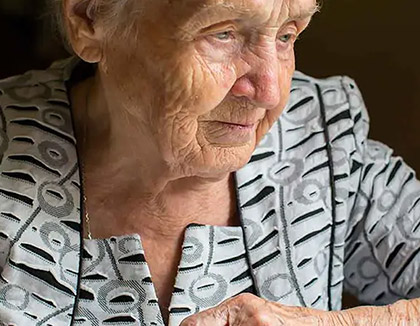 An elderly lady is using a laptop to find online resources.