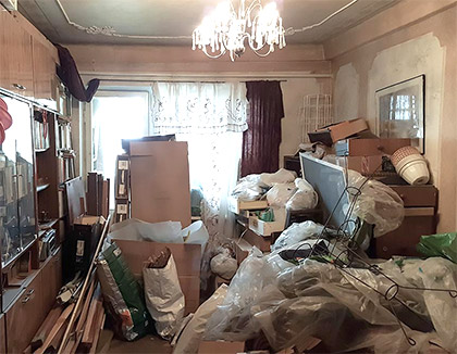 A front-room filled with rubbish, bags and boxes. These are piled up everywhere.